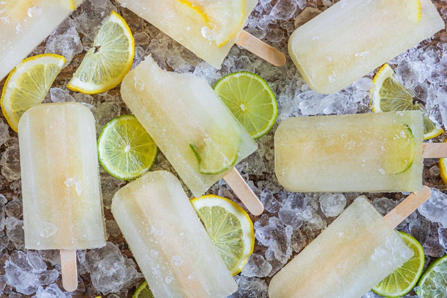 Homemade lemon and lime popsicles with fruit slices and wooden popsicle sitcks.
