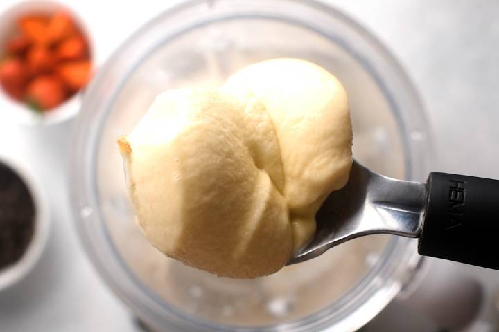 Banana Nice Cream (5 Flavor Ideas!) Scoop of banana nice cream above a blender.