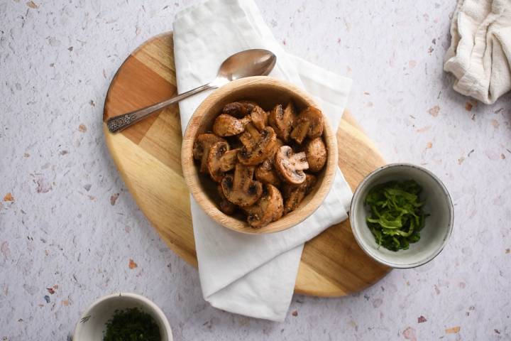 Roasted Mushrooms Roasted cremini mushrooms in a wooden bowl with fresh herbs,