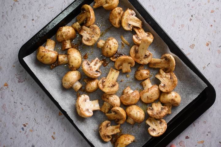 Roasted Mushrooms Mushroom halves spread out in a single layer on a baking sheet.