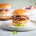 Easy Salmon Burgers Salmon burgers with fresh salmon and spices served on a bun with coleslaw.