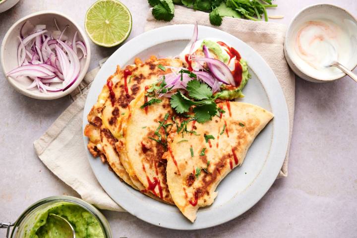 Ten Easy Quesadillas Recipes To Make Today Buffalo chicken quesadillas cut into triangles with buffalo sauce drizzled on top.