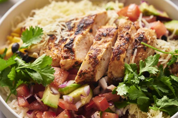 34 Easy Rice Bowl Recipes Rice bowl with cooked chicken, black beans, corn, pico de gallo, avocado, and cheese.