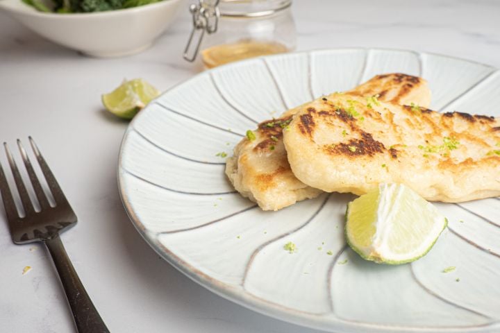 Honey Lime Tilapia Tilapia with honey and lime cooked until crispy on a plate with a lime and fork.