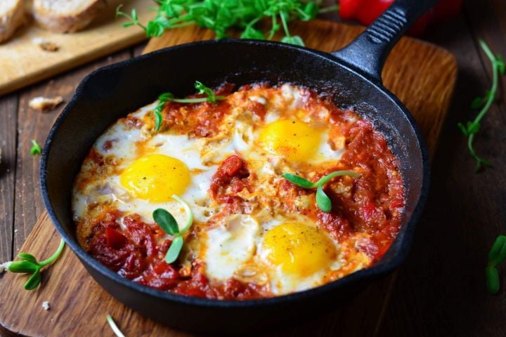 Baked Eggs with Tomatoes and Parmesan Baked eggs in tomato sauce with parmesan cheese on top in a cast iron skillet.