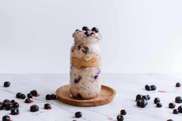 Blueberry Overnight Oatmeal Blueberry overnight oatmeal with almond butter in a mason jar with blueberries on the side.