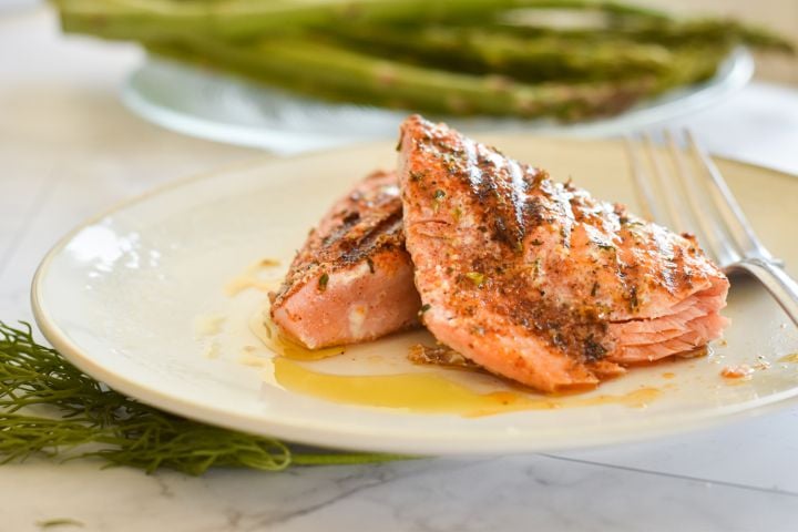 Easy Grilled Salmon with Cajun Seasoning Grilled salmon with a Cajun spice rub on a plate with asparagus and salad./