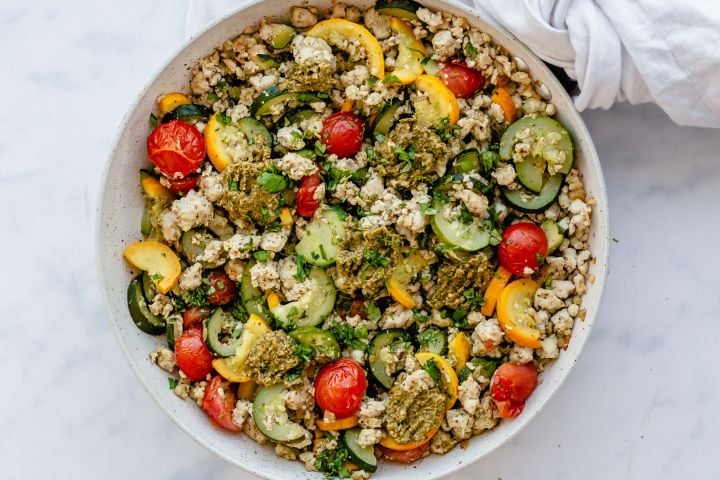 Pesto Ground Turkey with Zucchini Ground turkey, zucchini, yellow squash, and cherry tomatoes in a skillet and topped with pesto.