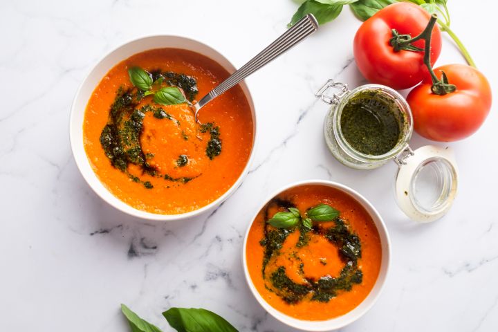 Roasted Tomato Basil Soup Roasted tomato basil soup in two bowls with pesto and fresh basil leaves.
