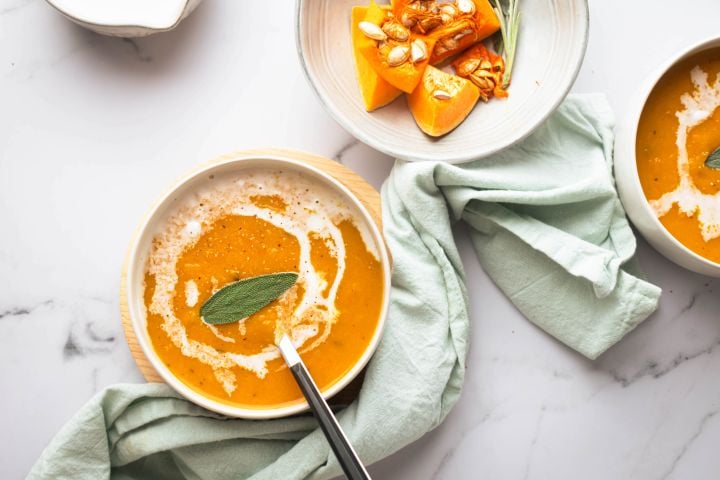 Slow Cooker Butternut Squash Soup (Three Ways!) Slow cooker butternut squash soup in two bowls with a sage leaf on top.