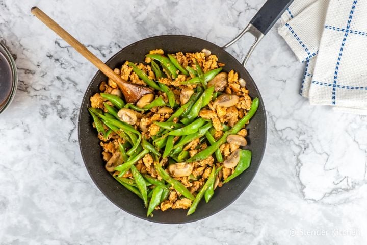 Spicy Turkey, Green Bean, and Mushroom Stirfry Spicy Ground Turkey stir fry with green beans and mushrooms in a black skillet with a wooden spoon.