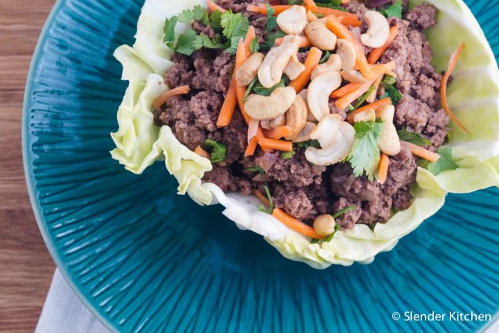 Thai Beef Cabbage Wraps Thai beef cabbage wraps with cashews, cilantro, and carrots on a plate.