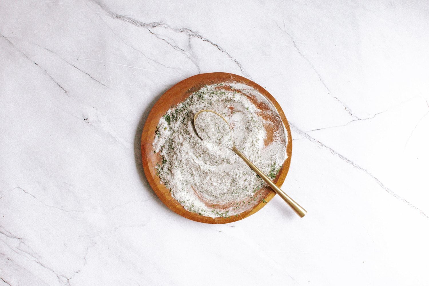Ranch spice mix on a wooden plate with buttermilk powder, garlic powder, onion powder, and dried herbs.
