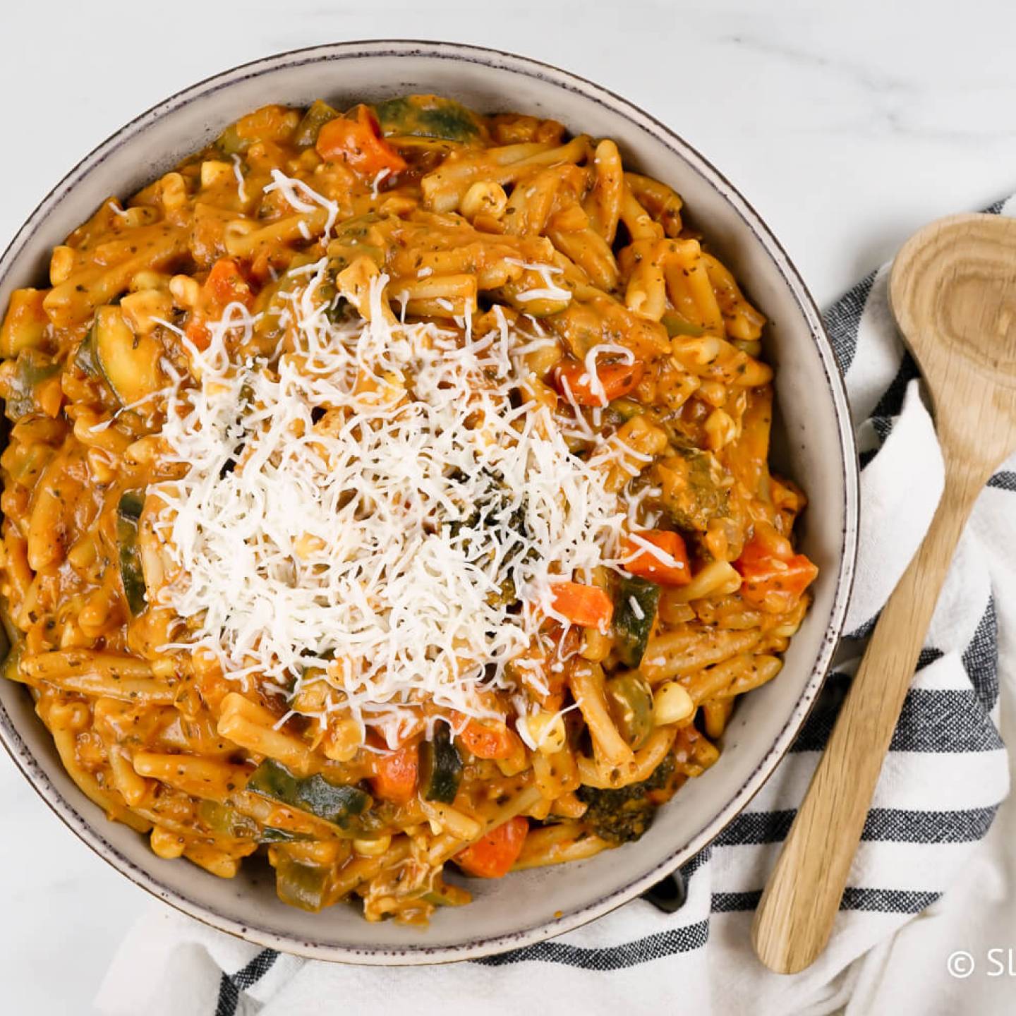 One pot creamy vegetable pasta with tomato sauce in bowl with mozzarella cheese.