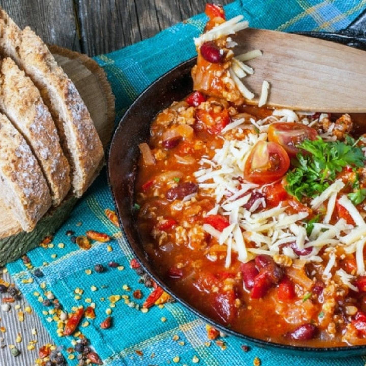 Pepperoni pizza chili in a blue bowl with slices of bread on the side.