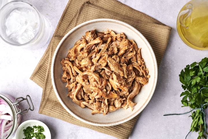 A bowl of shredded, seasoned chicken.