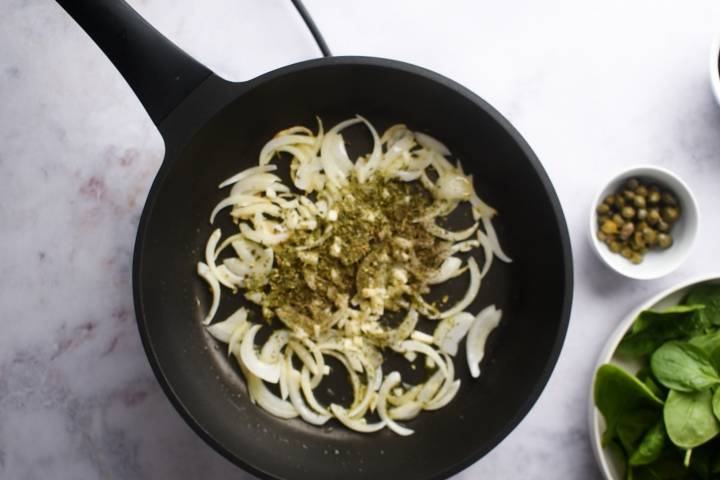 Onion slices, garlic, oregano, thyme, and red pepper flakes in a skillet.