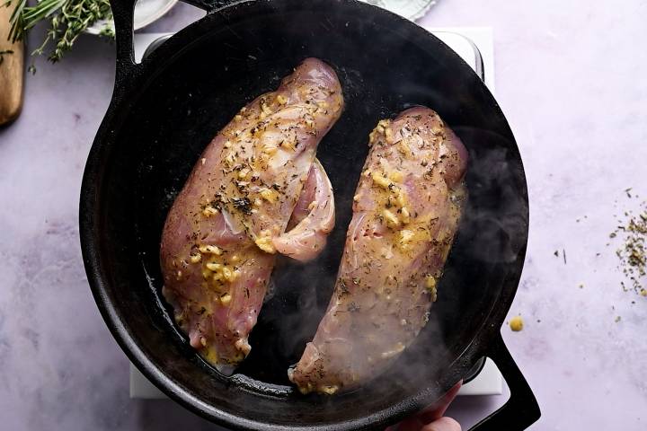Turkey tenderloins searing in a hot cast iron skillet.