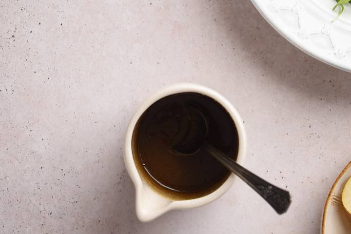 Balsamic vinegar, honey, mustard, olive oil, salt, and pepper in a small dish with a spoon.