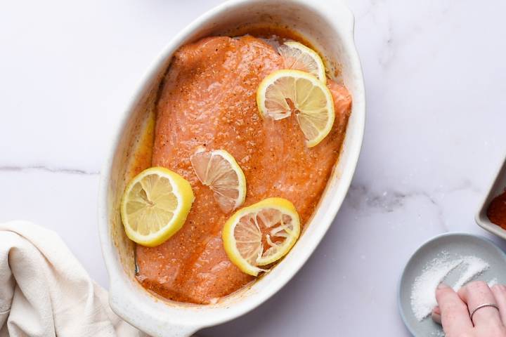 Salmon in a baking with lemon pepper and lemon slices.