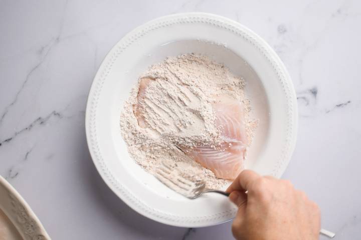 Cod fish being dredged in flour and spices.