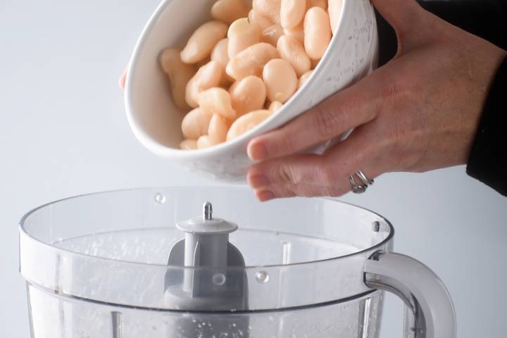 White beans being added to a food processor.