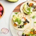 Butternut squash black bean tacos on corn tortillas with cilantro, cheese, avocado, and onions.