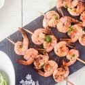 Garlic lemon shrimp kabobs on a piece of slate with garlic and parsley.