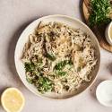 A plate of slow-cooked lemon garlic chicken, shredded and garnished with fresh parsley. 