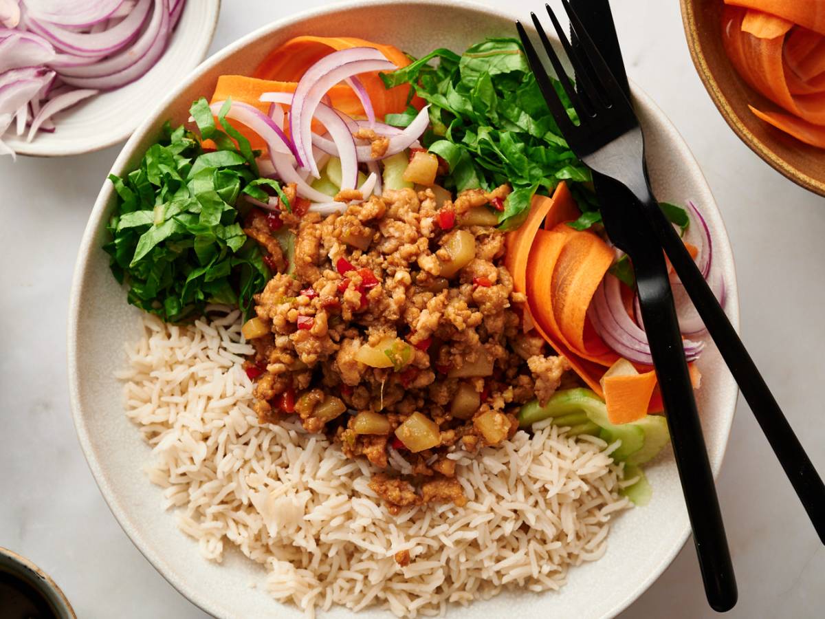 Asian ground turkey bowls with lean ground turkey, bell peppers, mushrooms, and water chestnuts served with rice, carrots, cucumbers, lettuce, and green onions.