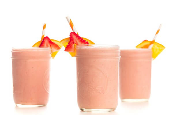 3 mason jar cups full of strawberry sunrise breakfast smoothies in a row.