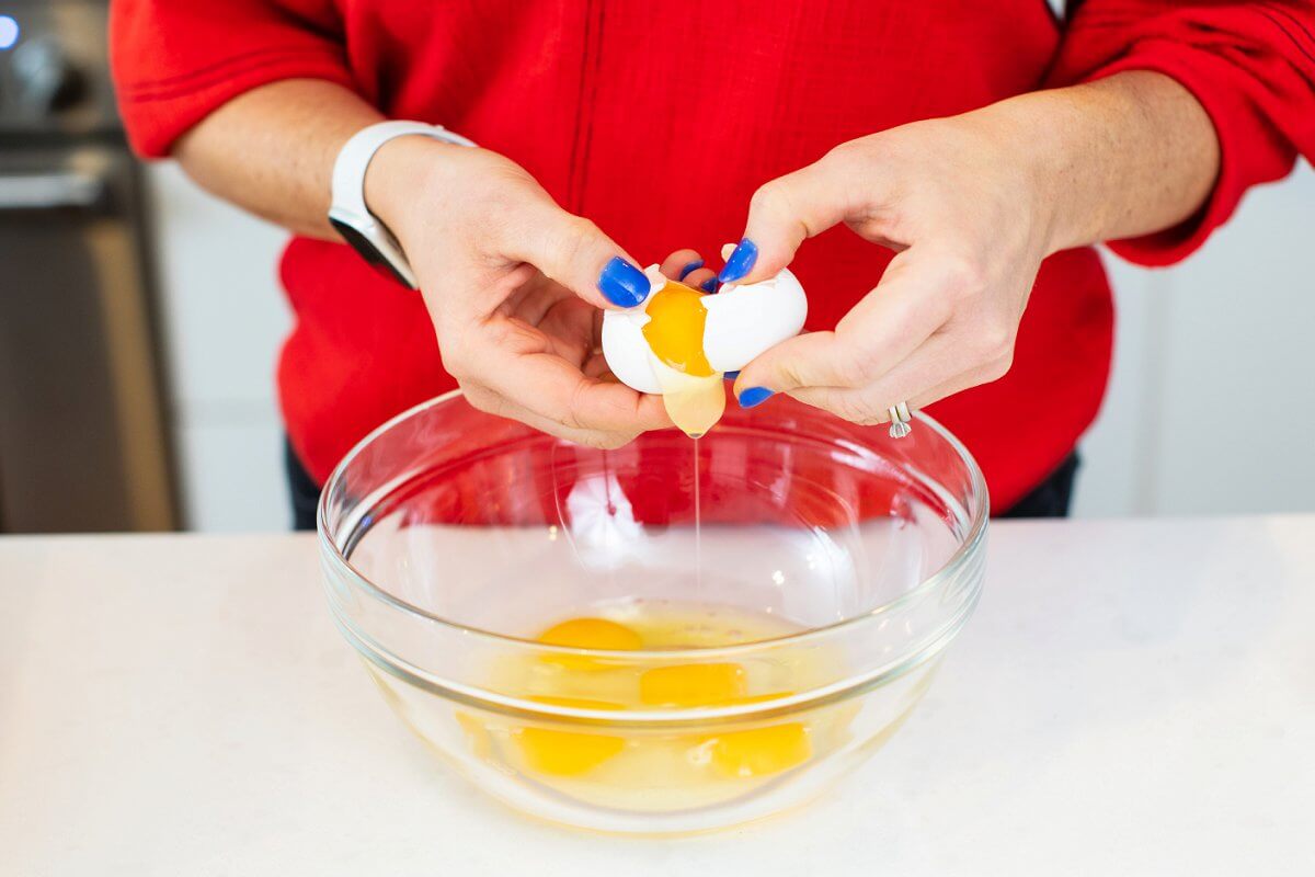 Liz cracking eggs into a large glass bowl.