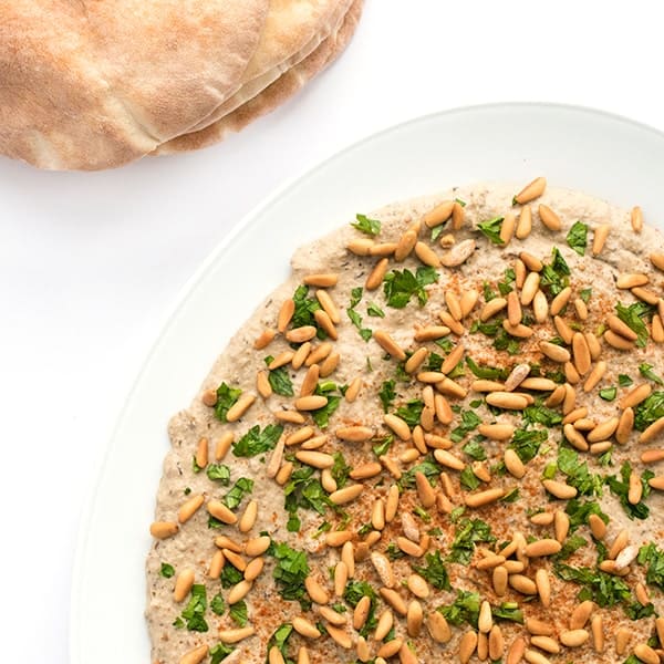 pine nuts and baba ganoush on a plate with pita bread