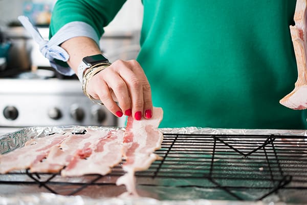 laying raw bacon on a pan