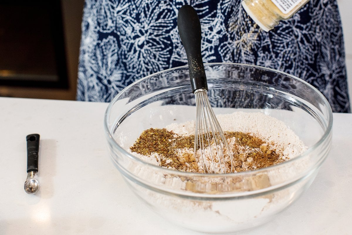 Liz standing behind a counter with a bowl of dry ingredients for pumpkin muffins and a whisk resting inside