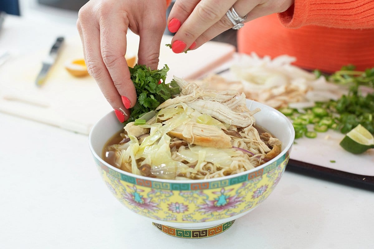 Liz adding garnish to spicy chicken ramen