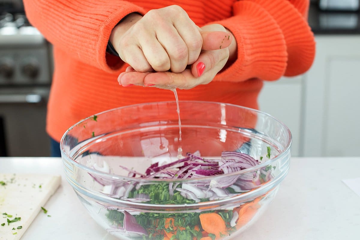 Liz squeezing fresh lemon juice on carrot salad.