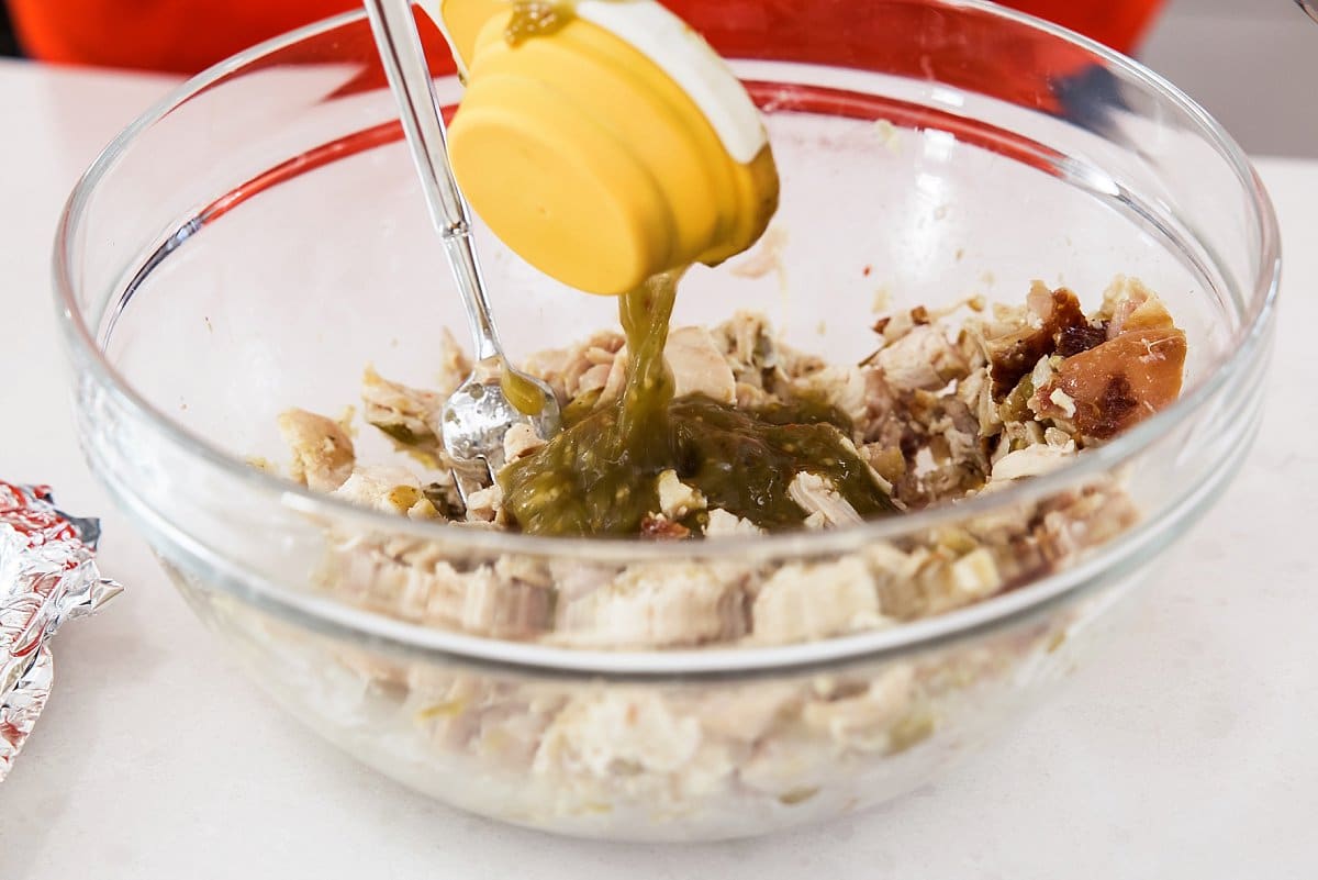 adding seasoning and salsa verde to chicken