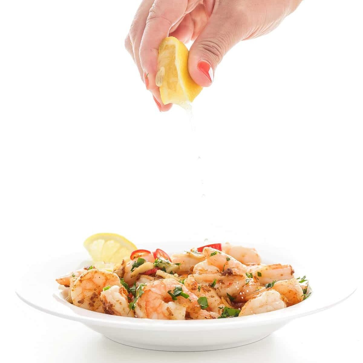 lemon being squeezed onto shrimp