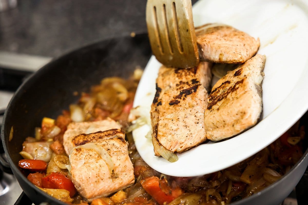 Cooked salmon being added back to pan.
