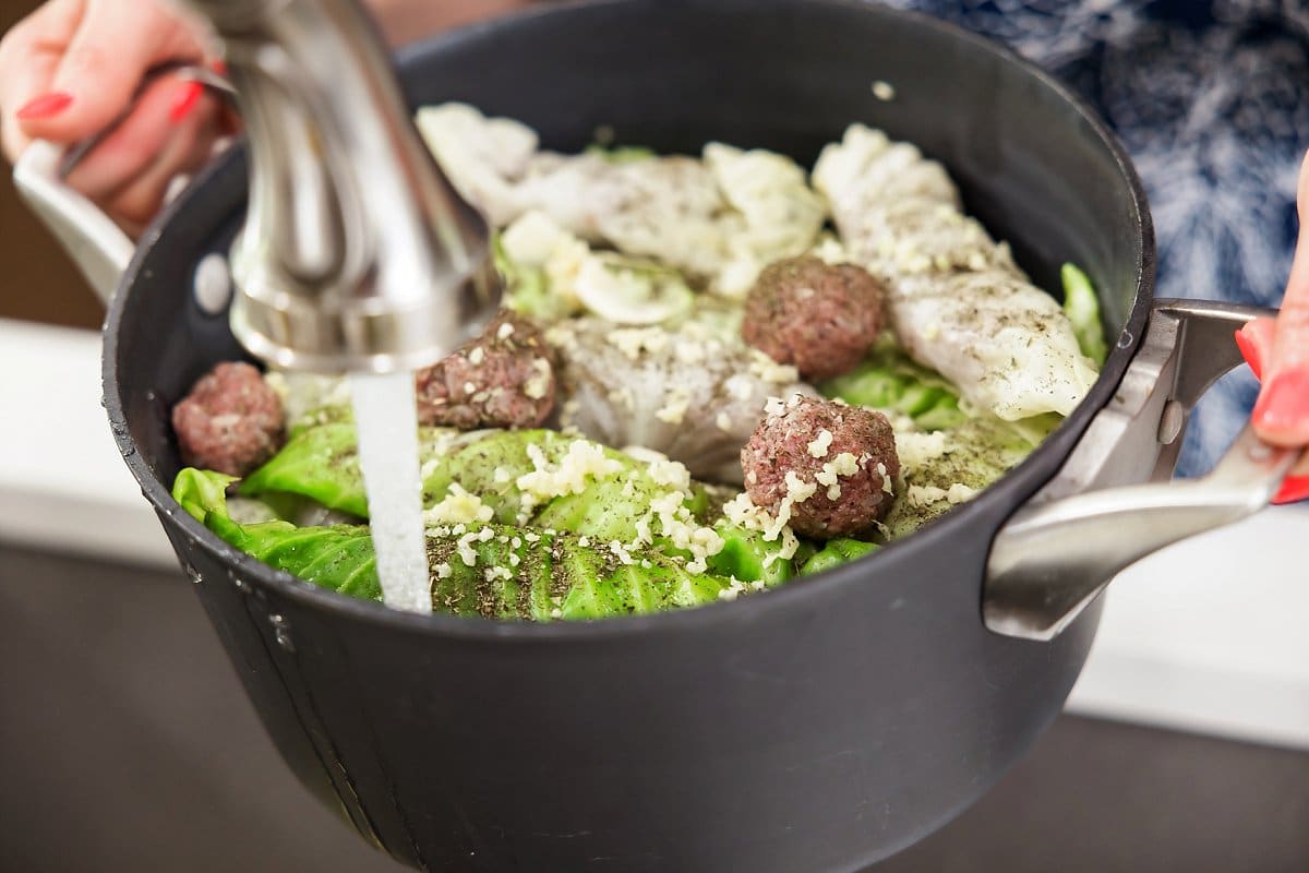 water being added to a pot full of cabbage rolls
