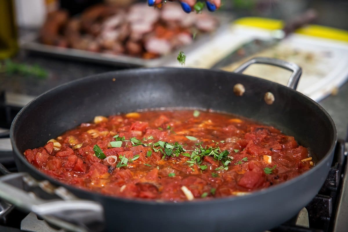 adding tomatoes to a pan