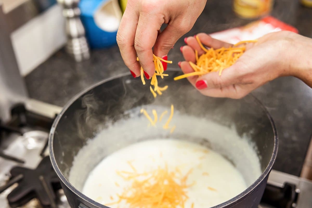 Liz adding cheese to cheese sauce.
