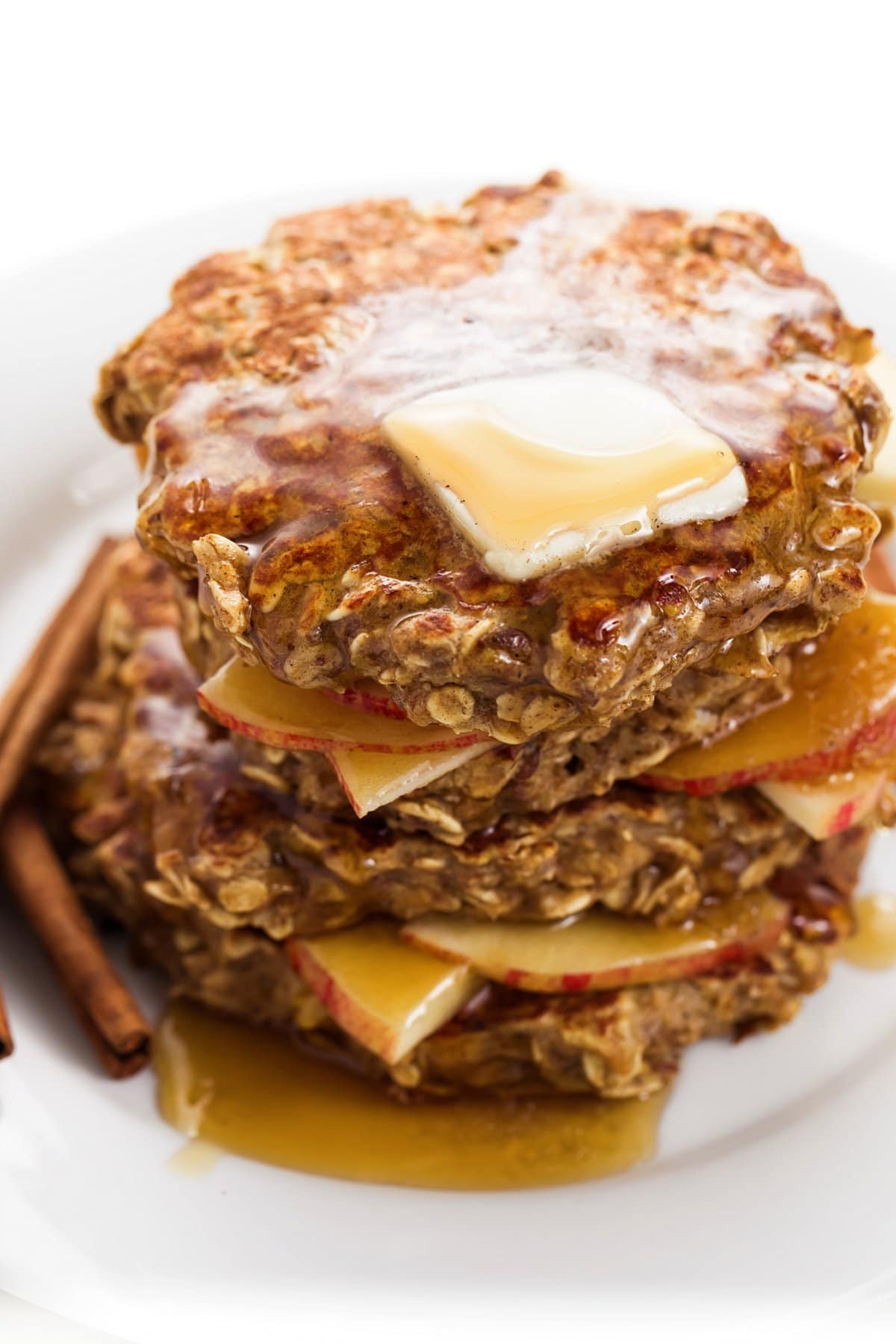 Apple cinnamon protein pancakes on a plate topped with butter and maple syrup.