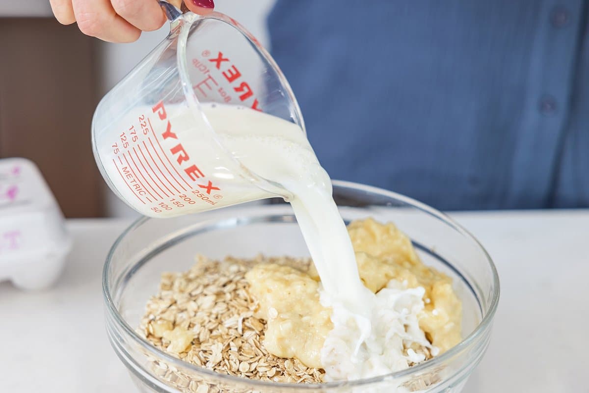 Liz pouring milk into batter in a bowl.