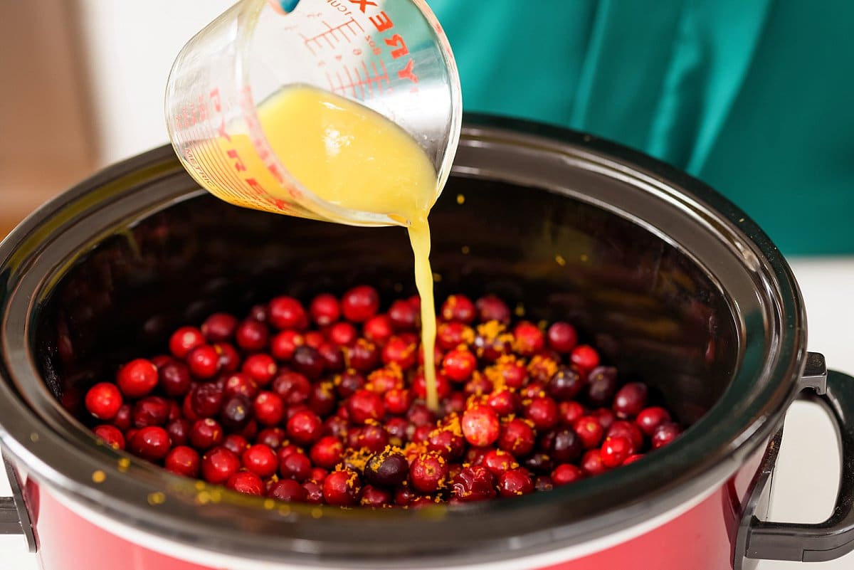 orange juice being poured onto cranberries