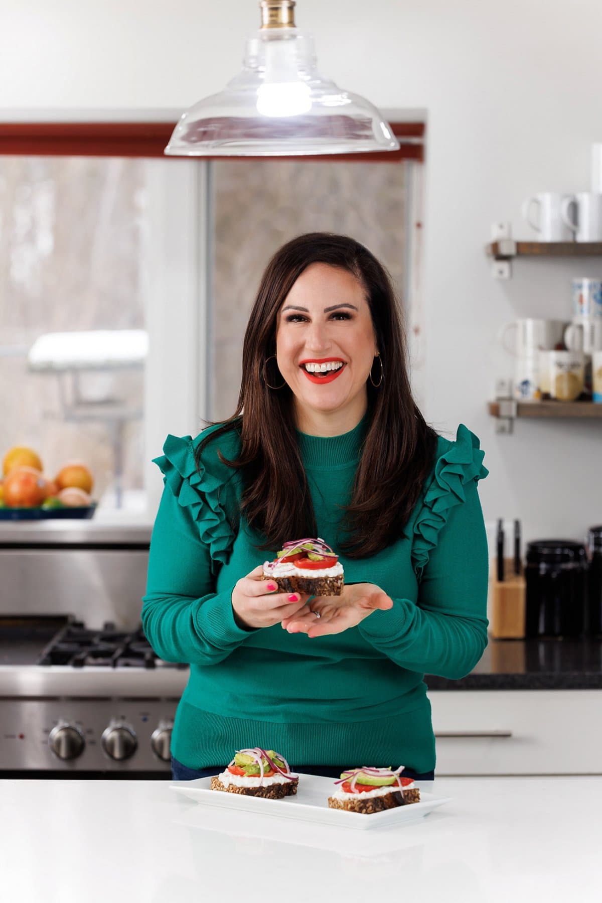 Liz eating avocado toast with cottage cheese and tomatoes.