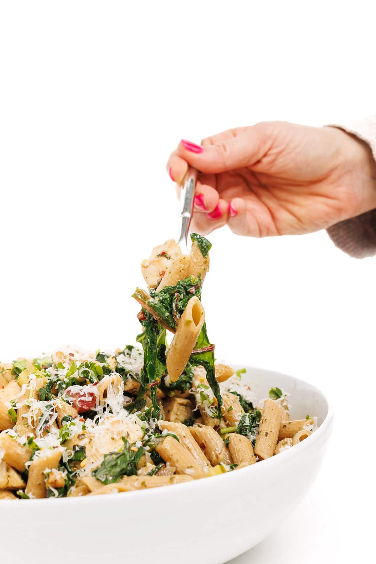 Forkful of pesto chicken pasta with Swiss chard.