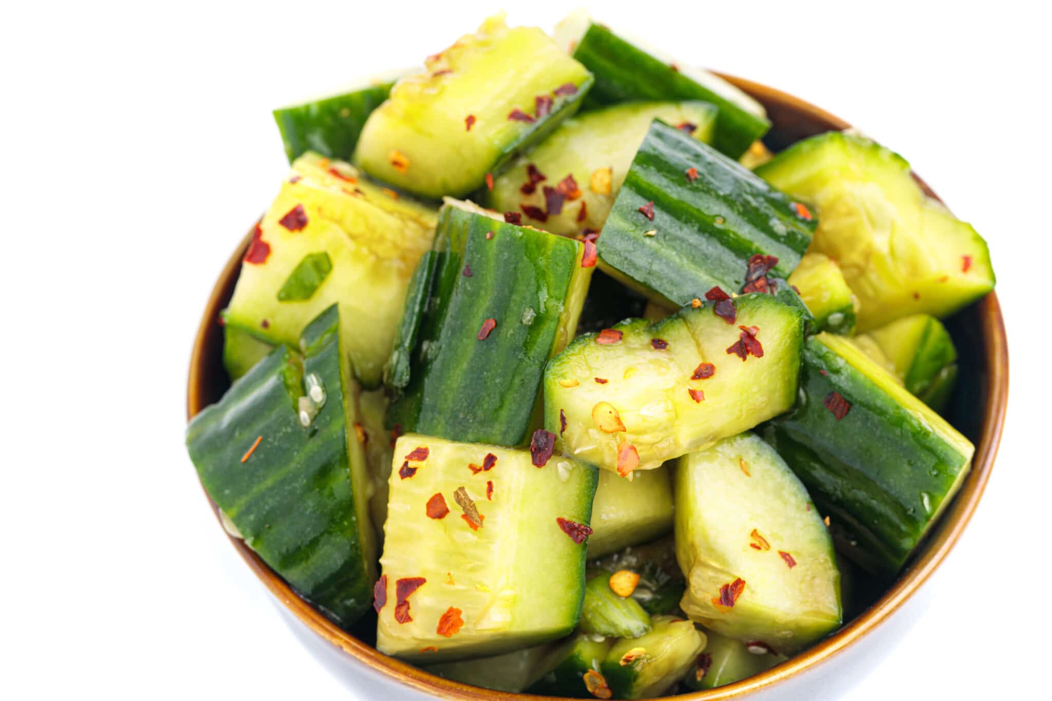 Chinese smashed cucumbers in a bowl topped with chili flakes.