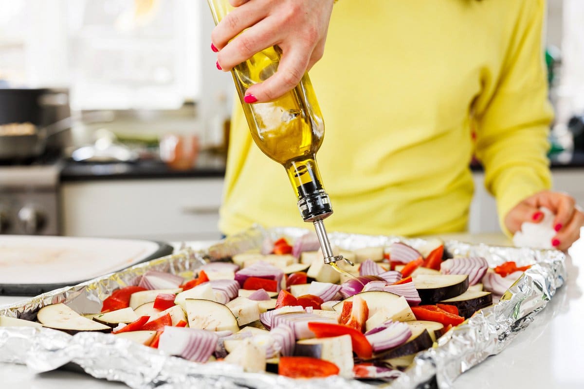 Drizzling olive oil on sheet pan of vegetables